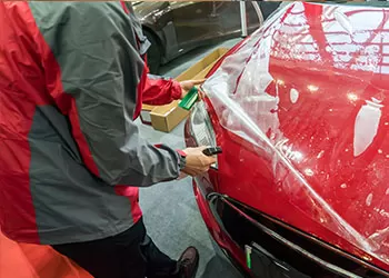 paint protection film being applied to a red car