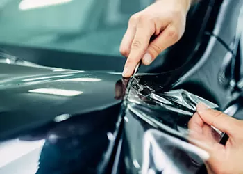 paint protection film being applied to a black car